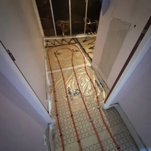 Pose de plancher chauffant hydraulique dans un couloir étroit après isolation en mousse polyuréthane projetée