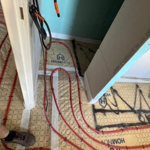 Raccordement des tubes de chauffage au sol et gaines techniques à travers une cloison en plaque de plâtre